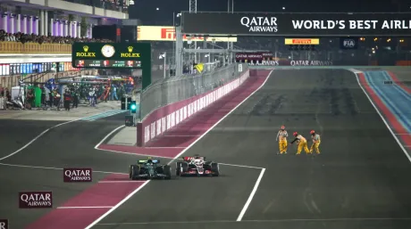 Fernando Alonso y Kevin Magnussen a la salida de boxes, con los comisarios limpiando la pista